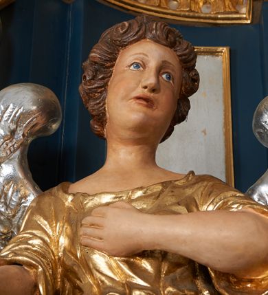 Zdjęcie nr 15: Ołtarz architektoniczny, trójosiowy, jednokondygnacyjny ze zwieńczeniem, na cokole. Mensa kamienna z portatylem. Antepedium proste, bez dekoracji, kamienne. Tabernakulum prostopadłościenne, ujęte pilastrami ustawionymi pod kątem, ze zwróconymi przeciwstawnie wolutami, zamiast trzonów, zwieńczone niepełnym belkowaniem. Drzwiczki w formie stojącego prostokąta zamkniętego łukiem półkolistym z krzyżem w polu. Retabulum ujęte parami pilastrów i kolumn o skręconych trzonach oraz kapitelach kompozytowych, dźwigających niepełne belkowanie z wydatnym gzymsem, wyłamanym w osiach podpór, przerwane w polu środkowym. Na gzymsie para puttów trzymających arma Christi. Osie boczne ustawione pod kątem względem lica ołtarza, w nich ustawiony dwie figury stojących aniołów. W polu środkowym ołtarza rama w formie stojącego prostokąta mieszcząca obraz św. Teresy z Lisieux. Zwieńczenie ołtarza w kształcie owalnego medalionu ujętego wydatnymi spływami wolutowymi. W polu owalny obraz przedstawiający wskrzeszenie Piotrowina. Kondygnacja pierwsza nastawy ujęta uszami utworzonymi z akantu. Cokoły podpór ozdobione z trzech stron płycinami z dekoracją roślinną w postaci liści i kwiatów. Na osi pilastrów cokoły podparte potrójną wolutą i parą girland owocowych. Trzony pilastrów i osie boczne dekorowane płycinami. Trzony kolumn zdobione ornamentem roślinnym. W polu środkowym ołtarza rama obrazu dekorowana akantem; u jej spodu akant i uskrzydlona główka anielska, zwieńczona akantem z palmetą. W zwieńczeniu profilowana rama dekorowana miejscami akantem, ujęta muszlą; woluty i lizeny zdobione kampanulami. Struktura ołtarza polichromowana na ciemnogranatowo ze złoconymi i srebrzonymi elementami architektonicznymi i ornamentyką.