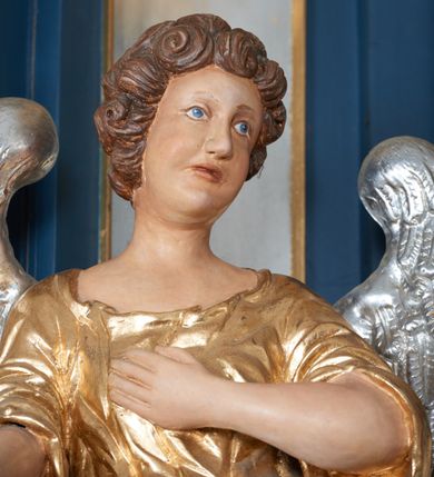 Zdjęcie nr 16: Ołtarz architektoniczny, trójosiowy, jednokondygnacyjny ze zwieńczeniem, na cokole. Mensa kamienna z portatylem. Antepedium proste, bez dekoracji, kamienne. Tabernakulum prostopadłościenne, ujęte pilastrami ustawionymi pod kątem, ze zwróconymi przeciwstawnie wolutami, zamiast trzonów, zwieńczone niepełnym belkowaniem. Drzwiczki w formie stojącego prostokąta zamkniętego łukiem półkolistym z krzyżem w polu. Retabulum ujęte parami pilastrów i kolumn o skręconych trzonach oraz kapitelach kompozytowych, dźwigających niepełne belkowanie z wydatnym gzymsem, wyłamanym w osiach podpór, przerwane w polu środkowym. Na gzymsie para puttów trzymających arma Christi. Osie boczne ustawione pod kątem względem lica ołtarza, w nich ustawiony dwie figury stojących aniołów. W polu środkowym ołtarza rama w formie stojącego prostokąta mieszcząca obraz św. Teresy z Lisieux. Zwieńczenie ołtarza w kształcie owalnego medalionu ujętego wydatnymi spływami wolutowymi. W polu owalny obraz przedstawiający wskrzeszenie Piotrowina. Kondygnacja pierwsza nastawy ujęta uszami utworzonymi z akantu. Cokoły podpór ozdobione z trzech stron płycinami z dekoracją roślinną w postaci liści i kwiatów. Na osi pilastrów cokoły podparte potrójną wolutą i parą girland owocowych. Trzony pilastrów i osie boczne dekorowane płycinami. Trzony kolumn zdobione ornamentem roślinnym. W polu środkowym ołtarza rama obrazu dekorowana akantem; u jej spodu akant i uskrzydlona główka anielska, zwieńczona akantem z palmetą. W zwieńczeniu profilowana rama dekorowana miejscami akantem, ujęta muszlą; woluty i lizeny zdobione kampanulami. Struktura ołtarza polichromowana na ciemnogranatowo ze złoconymi i srebrzonymi elementami architektonicznymi i ornamentyką.