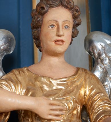 Zdjęcie nr 7: Ołtarz architektoniczny, trójosiowy, jednokondygnacyjny ze zwieńczeniem, na cokole. Mensa kamienna z portatylem. Antepedium proste, bez dekoracji, kamienne. Tabernakulum prostopadłościenne, ujęte pilastrami ustawionymi pod kątem, ze zwróconymi przeciwstawnie wolutami, zamiast trzonów, zwieńczone niepełnym belkowaniem. Drzwiczki w formie stojącego prostokąta zamkniętego łukiem półkolistym z krzyżem w polu. Retabulum ujęte parami pilastrów i kolumn o skręconych trzonach oraz kapitelach kompozytowych, dźwigających niepełne belkowanie z wydatnym gzymsem, wyłamanym w osiach podpór, przerwane w polu środkowym. Na gzymsie para puttów trzymających arma Christi. Osie boczne ustawione pod kątem względem lica ołtarza, w nich ustawiony dwie figury stojących aniołów. W polu środkowym ołtarza rama w formie stojącego prostokąta mieszcząca obraz św. Teresy z Lisieux. Zwieńczenie ołtarza w kształcie owalnego medalionu ujętego wydatnymi spływami wolutowymi. W polu owalny obraz przedstawiający wskrzeszenie Piotrowina. Kondygnacja pierwsza nastawy ujęta uszami utworzonymi z akantu. Cokoły podpór ozdobione z trzech stron płycinami z dekoracją roślinną w postaci liści i kwiatów. Na osi pilastrów cokoły podparte potrójną wolutą i parą girland owocowych. Trzony pilastrów i osie boczne dekorowane płycinami. Trzony kolumn zdobione ornamentem roślinnym. W polu środkowym ołtarza rama obrazu dekorowana akantem; u jej spodu akant i uskrzydlona główka anielska, zwieńczona akantem z palmetą. W zwieńczeniu profilowana rama dekorowana miejscami akantem, ujęta muszlą; woluty i lizeny zdobione kampanulami. Struktura ołtarza polichromowana na ciemnogranatowo ze złoconymi i srebrzonymi elementami architektonicznymi i ornamentyką.