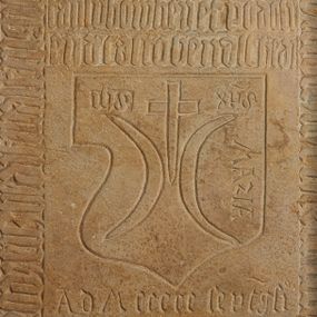 Zdjęcie nr 1: Piaskowcowa płyta nagrobna w formie stojącego prostokąta, ujęta profilowaną, drewnianą ramą. W centrum wyryte dwa herby, większy Ostoja z inskrypcjami „IHS XPS” oraz „MArIA”, poniżej nieco mniejszy herb Radwan oraz data „A(nno) d(omini) MCCCCC sept(ua)g(e)si[mo]”. W otoku płyty znajduje się minuskułowa, gotycka inskrypcja „hic iacet generos(us) d[omi]n[u]s ioh[annes] [...] / [ge]n[er]osi d[omi]ni pauli de dmoscze / de cast[r]o ogrodze[n]icz he[re]dr filiast[er] m[a]gnifici \ d[omi]ni pr[ec]lai de dmoscze cap/tan[ei] lubowhen(si) et podoli/en(si) de cast[r]o ben(n)alth he[re]di”.