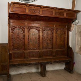Zdjęcie nr 1: Stalle czterosiedzeniowe, z wysokim, czteroosiowym zapieckiem i baldachimem. Zaplecek artykułowany umieszczonymi na cokołach pilastrami o kanelowanych trzonach, dźwigającymi architraw z tryglifami na osi podpór oraz gzyms dekorowany kostkowaniem. W polach zaplecka arkady w boniowanym obramieniu. W arkadach malowana dekoracja, naprzemiennie stelaż okuciowy wypełniony ornamentem roślinnym oraz arabeska. W partii cokołów malowane płyciny z dekoracją geometryczno-roślinną. 
Baldachim uniesiony skośnie w górę, od spodu dekorowany malowanymi płycinami z okuciami; zakończony pełnym belkowaniem; fryz dekorowany tryglifami i malowanymi płycinami z okuciami; wydatny gzyms z kostkowaniem i konsolkami. Dekoracja w płycinach i dwóch zapleckach uzyskana na zasadzie malarstwa patronowego; wzór ugrowy na tle brunatnym; w pozostałych zapleckach arabeska w odcieniach zieleni i różu. Obramienia płycin i boniowanie polichromowane na czerwono.