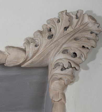 Zdjęcie nr 6: Naroża portalu do kaplicy ujęte wieńcami lauru i liśćmi akantu. Nad wejściem trzy putta trzymające otwartą księgę na tle monumentalnej glorii promienistej i obłoków. 