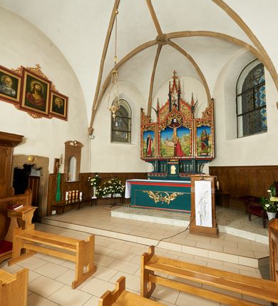 Zdjęcie nr 2: Ołtarz szafiasty, przyścienny, trójosiowy, jednokondygnacyjny ze zwieńczeniem. Mensa drewniana, prostopadłościenna. Antepedium z umieszczoną centralnie pseudopłyciną mieszczącą monogram IHS w akantowym otoku; boki zdobione, z lewej przedstawiony herb Łabędź. W części centralnej prostopadłościenne tabernakulum w formie kapliczki z ukośnie ustawionymi pilastrami zwieńczonymi pinaklami i kwiatonami. Predella u podstawy dekorowana fryzem palmetowym, wyżej pseudomaswerkowym, ostrołukowym ornamentem. Nastawa w formie tryptyku z neogotyckim, ażurowym zwieńczeniem zakończonym pinaklami i kwiatonem. Oś środkowa i osie boczne ujęte smukłymi, złoconymi kolumienkami o skręconych trzonach wspierającymi ażurową dekorację roślinną, w części centralnej uformowaną w kształt łuku w ośli grzbiet. W polu środkowym rzeźbiona scena Ukrzyżowania z figurą Chrystusa Ukrzyżowanego z klęczącą Marią Magdaleną obejmującą krzyż, umieszczona na tle górzystego pejzażu z widokiem Jerozolimy z lewej strony. W kwaterach bocznych, na tle pejzażu, płaskorzeźbione figury, po lewej stronie Maria na niewysokim postumencie z inskrypcją „S(ancta) Maria”, zwrócona w stronę krzyża; po prawej na postumencie z napisem „S(anctus) Johannes”, św. Jan Ewangelista trzymający kielich w lewej ręce. Wszystkie kwatery obwiedzione ramą ze złotą inskrypcją na czerwonym tle „Julianus de Skrzynno Dunin Brzeziński uxorque eius Eva cum matre sua Anastasia Morawska in honorem Dei Omnipotentis pro sua suorumque salute omniumque huius parochiae fidelium et prosperitiate et redemptione hoc jusferunt altare fieri A(nno) D(omini) 1892 salvo Leone XIII P(ontifice) M(aximo)”. Zwieńczenie ażurowe, płaskorzeźbione, w części centralnej powtarza kształt oślego grzbietu ze złoconym ornamentem stylizowanej wici roślinnej, w górnej części zamknięte pinaklami i kwiatonami. Kwatery boczne zwieńczone uszakami wypełnionymi ażurowym, złoconym suchym akantem, obwiedzione ornamentem ze stylizowanej wici roślinnej. Struktura malowana w odcieniu morskiej zieleni z czerwonymi detalami, ornamentyka złocona. Figury oraz tło kwater w pełni polichromowane.
