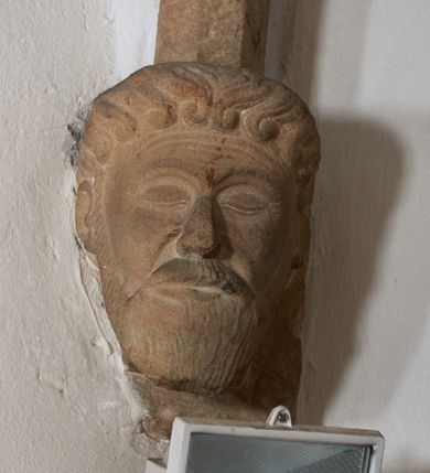 Zdjęcie nr 6: Komplet sześciu kamiennych konsol w formie męskich, brodatych głów, na które spływają żebra krzyżowego sklepienia w nawie głównej. Postać pierwsza o twarzy szerokiej, okolonej długim zarostem oraz włosami układającymi się w loki na czole. Oczy zamknięte, wydatny, prosty nos. Widoczne rurkowate bruzdy na czole. Postać druga o twarzy pociągłej, okolonej długim zarostem artykułowanym za pomocą rurkowatych fałd. Broda na końcu nieznacznie rozdwojona. Włosy proste ponad czołem tworzą trójkątne zakola. Oczy zamknięte, czoło pokryte bruzdami. Postać trzecia o trójkątnej twarzy z niskim, pokrytym bruzdami czołem i kręconych włosach. Oczy zamknięte. Postać czwarta o owalnej, pełnej twarzy, wystających kościach policzkowych. Zarost artykułowany za pomocą równoległych fałdek. Włosy układające się w loki ponad czołem. Oczy zamknięte. Postać piąta o szerokiej, płaskiej twarzy z gęstym zarostem. Długie, falowane wąsy, zamknięte oczy. Włosy ponad czołem układające się w loki. Postać szósta o pociągłej, podłużnej twarzy z zarostem. Długi, prosty nos, zamknięte oczy, niskie czoło ponad, którym bujne, proste włosy. Na przecięciach żeber dwa polichromowane zworniki z godłem herbu Drużyna oraz syglami „S(ebastian) L(ubomirski)" umieszczonymi na czerwonym tle, pierwszy ośmioboczny, drugi w kształcie wieloliścia. W podniebiu arkady tęczowej wolutowa konsola ustawiona na kapitelu pilastra w podniebiu łuku tęczowego. U podstawy konsoli, na osi umieszczony rollwerkowy kartusz mieszczący godło herbu Drużyna oraz sygle „S(ebastian) L(ubomirski)”. 