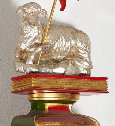 Zdjęcie nr 1: Pełnoplastyczna, wolnostojąca figura Baranka leżącego na zamkniętej księdze; z chorągwią pashalną. Całość umieszczona na wklęsło-wypukłym postumencie na planie odcinka koła. Postument i chorągiew polichromowane w kolorach czerwonym i zielonym oraz złocone, baranek srebrzony.