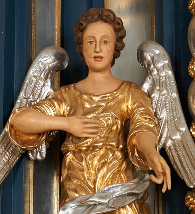 Zdjęcie nr 1: Para pełnoplastycznych, drążonych od tyłu, polichromowanych, złoconych i srebrzonych rzeźb przedstawiających stojące anioły w dynamicznych pozach. Figury przedstawione w kontrapoście, ustawione na niewielkich postumentach. Ubrane w długie, bogato drapowane, złocone suknie oraz rozwiane srebrzone płaszcze. Stopy bose. Obie postaci wykonują analogiczne gesty, składając jedną rękę na piersi, drugą wyciągając lekko do przodu. Twarze owalne, pełne z wydatnymi policzkami oraz podbródkami okolone jasnobrązowymi, kręconymi włosami. Karnacje polichromowane, skrzydła srebrzone.