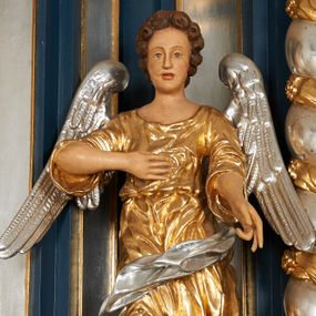 Zdjęcie nr 1: Para pełnoplastycznych, drążonych od tyłu, polichromowanych, złoconych i srebrzonych rzeźb przedstawiających stojące anioły w dynamicznych pozach. Figury przedstawione w kontrapoście, ustawione na niewielkich postumentach. Ubrane w długie, bogato drapowane, złocone suknie oraz rozwiane srebrzone płaszcze. Stopy bose. Obie postaci wykonują analogiczne gesty, składając jedną rękę na piersi, drugą wyciągając lekko do przodu. Twarze owalne, pełne z wydatnymi policzkami oraz podbródkami okolone jasnobrązowymi, kręconymi włosami. Karnacje polichromowane, skrzydła srebrzone.