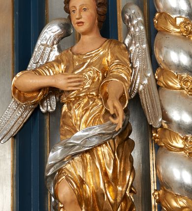 Zdjęcie nr 10: Para pełnoplastycznych, drążonych od tyłu, polichromowanych, złoconych i srebrzonych rzeźb przedstawiających stojące anioły w dynamicznych pozach. Figury przedstawione w kontrapoście, ustawione na niewielkich postumentach. Ubrane w długie, bogato drapowane, złocone suknie oraz rozwiane srebrzone płaszcze. Stopy bose. Obie postaci wykonują analogiczne gesty, składając jedną rękę na piersi, drugą wyciągając lekko do przodu. Twarze owalne, pełne z wydatnymi policzkami oraz podbródkami okolone jasnobrązowymi, kręconymi włosami. Karnacje polichromowane, skrzydła srebrzone.