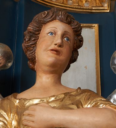 Zdjęcie nr 6: Para pełnoplastycznych, drążonych od tyłu, polichromowanych, złoconych i srebrzonych rzeźb przedstawiających stojące anioły w dynamicznych pozach. Figury przedstawione w kontrapoście, ustawione na niewielkich postumentach. Ubrane w długie, bogato drapowane, złocone suknie oraz rozwiane srebrzone płaszcze. Stopy bose. Obie postaci wykonują analogiczne gesty, składając jedną rękę na piersi, drugą wyciągając lekko do przodu. Twarze owalne, pełne z wydatnymi policzkami oraz podbródkami okolone jasnobrązowymi, kręconymi włosami. Karnacje polichromowane, skrzydła srebrzone.