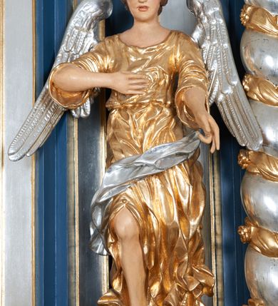 Zdjęcie nr 9: Para pełnoplastycznych, drążonych od tyłu, polichromowanych, złoconych i srebrzonych rzeźb przedstawiających stojące anioły w dynamicznych pozach. Figury przedstawione w kontrapoście, ustawione na niewielkich postumentach. Ubrane w długie, bogato drapowane, złocone suknie oraz rozwiane srebrzone płaszcze. Stopy bose. Obie postaci wykonują analogiczne gesty, składając jedną rękę na piersi, drugą wyciągając lekko do przodu. Twarze owalne, pełne z wydatnymi policzkami oraz podbródkami okolone jasnobrązowymi, kręconymi włosami. Karnacje polichromowane, skrzydła srebrzone.