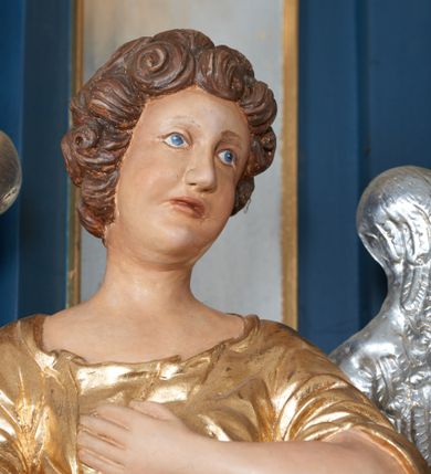 Zdjęcie nr 7: Para pełnoplastycznych, drążonych od tyłu, polichromowanych, złoconych i srebrzonych rzeźb przedstawiających stojące anioły w dynamicznych pozach. Figury przedstawione w kontrapoście, ustawione na niewielkich postumentach. Ubrane w długie, bogato drapowane, złocone suknie oraz rozwiane srebrzone płaszcze. Stopy bose. Obie postaci wykonują analogiczne gesty, składając jedną rękę na piersi, drugą wyciągając lekko do przodu. Twarze owalne, pełne z wydatnymi policzkami oraz podbródkami okolone jasnobrązowymi, kręconymi włosami. Karnacje polichromowane, skrzydła srebrzone.