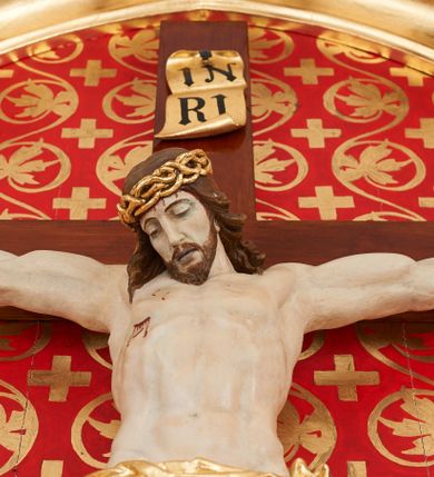 Zdjęcie nr 3: Pełnoplastyczna, polichromowana figura przedstawiająca ukrzyżowanego Chrystusa. Ciało muskularne o dobrze oddanej budowie anatomicznej z wyeksponowaną raną w prawym boku postaci. Głowa okolona długimi, brązowymi włosami, w cierniowej, złoconej koronie, opuszczona w dół i skierowana lekko w prawo. Twarz podłużna z zamkniętymi oczami, długim, prostym nosem oraz lekko rozchylonymi, sinymi ustami. Perizonium krótkie, złocone, udrapowane na lewym boku postaci. Stopy przebite jednym gwoździem. U szczytu pionowej belki krzyża złocony titulus z napisem „IN/RI”.