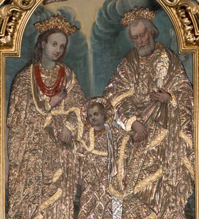 Zdjęcie nr 1: Obraz w kształcie stojącego prostokąta zamkniętego łukiem nadwieszonym, przedstawiająca Świętą Rodzinę. W centrum kompozycji mały Jezus trzyma za dłonie stojącego po prawej stronie obrazu św. Józefa oraz ukazaną po lewej stronie Matkę Boską. Postacie ukazane frontalnie, w postawie stojącej, Jezus z głową skierowaną w prawą stronę. Ponad nimi u góry nadlatująca gołębica Ducha Świętego. Maria przedstawiona jako młoda kobieta o pełnej, owalnej twarzy, okolonej długimi i falowanymi włosami. Prawą rękę wspiera na piersi, lewą trzyma za rękę Dzieciątko Jezus. Chrystus o pełnej, dziecięcej twarzy, okolonej jasnymi i krótkimi włosami. Święty Józef ukazany jako starszy mężczyzna z dłuższymi i siwymi włosami oraz krótką, gęstą brodą. Lewą rękę podtrzymuje rąbek szat, prawą trzyma za rękę Jezusa. Święty Józef oraz Matka Boska w koronach na głowie; wszystkie postacie w butach oraz długich i bogato drapowanych szatach przykrytych pozłacanymi sukienkami. W tle wypełniony roślinnością pejzaż oraz obłoki. Po lewej stronie św. Józefa gałązka białej lilii. Również na gołębicę Ducha Świętego nałożona srebrna sukienka. Kolorystyka chłodna, pociemniała. Rama drewniana, profilowana, złocona, zdobiona liśćmi stylizowanego akantu. 