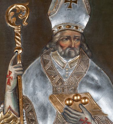 Zdjęcie nr 3: Obraz z wizerunkiem św. Mikołaja, ukazanego w całej postaci, frontalnie, w stroju przykrytym srebrną, miejscami złoconą  sukienką. Twarz okolona siwą brodą, nos prosty, oczy ciemne otwarte. Święty jest ubrany w srebrną albę, dekorowaną pasem złotej koronki, stułę i kapę z szerokimi złotymi brzegami, którą ma spiętą pod szyją. Na głowie ma infułę, na dłoniach długie rękawiczki, na stopach buty; rękawiczki i buty są zdobione czerwonymi krzyżami. W prawej ręce trzyma pastorał, a lewą przytrzymuje zamkniętą, złotą księgę z trzema złotymi kulami leżącymi na oprawie. Przy lewej krawędzi płótna, na dole postać tego samego świętego ponad cembrzykiem, w którym stoi trzech nagich młodzieńców.  Tło jednolite, ciemne. Obraz ujęty cienką, profilowaną, złoconą ramą. 