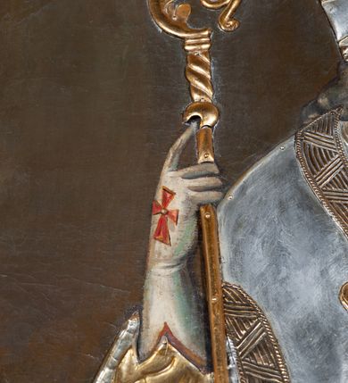 Zdjęcie nr 6: Obraz z wizerunkiem św. Mikołaja, ukazanego w całej postaci, frontalnie, w stroju przykrytym srebrną, miejscami złoconą  sukienką. Twarz okolona siwą brodą, nos prosty, oczy ciemne otwarte. Święty jest ubrany w srebrną albę, dekorowaną pasem złotej koronki, stułę i kapę z szerokimi złotymi brzegami, którą ma spiętą pod szyją. Na głowie ma infułę, na dłoniach długie rękawiczki, na stopach buty; rękawiczki i buty są zdobione czerwonymi krzyżami. W prawej ręce trzyma pastorał, a lewą przytrzymuje zamkniętą, złotą księgę z trzema złotymi kulami leżącymi na oprawie. Przy lewej krawędzi płótna, na dole postać tego samego świętego ponad cembrzykiem, w którym stoi trzech nagich młodzieńców.  Tło jednolite, ciemne. Obraz ujęty cienką, profilowaną, złoconą ramą. 