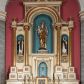 Zdjęcie nr 1: Nastawa ołtarzowa jednokondygnacyjna ze zwieńczeniem, trójosiowa, na cokole. Mensa prostopadłościenna, antepedium podzielone na cztery pola, wydzielone pięcioma kolumienkami, między nimi płyciny w kształcie stojących prostokątów zakończonych łukami półokrągłymi. Na mensie tron wystawienia w formie niszy ujęty parą smukłych kolumienek podtrzymujących szerokie belkowanie; w niszy krucyfiks. Cokół nastawy dekorowany prostokątami z imitacją marmoryzacji. Pierwsza kondygnacja utworzona z trzech arkad wydzielonych kolumnami, oś środkowa wyższa i szersza od bocznych. W polu środkowym figura Matki Boskiej Różańcowej w archiwolcie ujętej kolumienkami, w bocznych figury św. Dominika z lewej i św. Katarzyny Sieneńskiej z prawej strony. Poniżej cokołów postaci plakiety ornamentalne. Kolumny na zdwojonych cokołach, tak jak belkowanie powyżej wyłamane na ich osiach. Cokoły w dekorowane płycinami. Kondygnacja zamknięta belkowaniem przechodzącym w arkadę ponad polem centralnym, archiwolty dekorowane ornamentem roślinnym i geometrycznym. Zwieńczenie w formie leżącego prostokąta, tworzącego wysunięty szczyt, ponad którym krzyż łaciński na cokole ujętym spływami. Pola wypełniają rozety. 
Struktura polichromowana w kolorze kremowym; nisze niebieskie, płyciny i profilowania w kolorze czerwonym oraz szarym, elementy dekoracyjne złocone.
