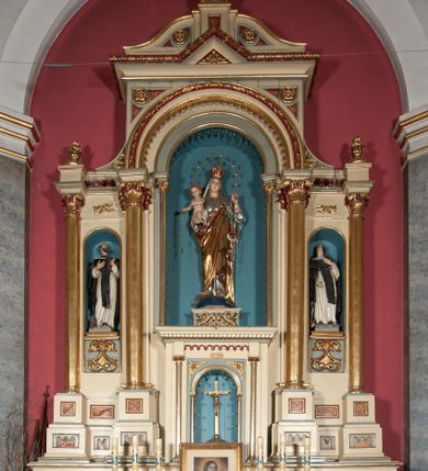 Zdjęcie nr 1: Nastawa ołtarzowa jednokondygnacyjna ze zwieńczeniem, trójosiowa, na cokole. Mensa prostopadłościenna, antepedium podzielone na cztery pola, wydzielone pięcioma kolumienkami, między nimi płyciny w kształcie stojących prostokątów zakończonych łukami półokrągłymi. Na mensie tron wystawienia w formie niszy ujęty parą smukłych kolumienek podtrzymujących szerokie belkowanie; w niszy krucyfiks. Cokół nastawy dekorowany prostokątami z imitacją marmoryzacji. Pierwsza kondygnacja utworzona z trzech arkad wydzielonych kolumnami, oś środkowa wyższa i szersza od bocznych. W polu środkowym figura Matki Boskiej Różańcowej w archiwolcie ujętej kolumienkami, w bocznych figury św. Dominika z lewej i św. Katarzyny Sieneńskiej z prawej strony. Poniżej cokołów postaci plakiety ornamentalne. Kolumny na zdwojonych cokołach, tak jak belkowanie powyżej wyłamane na ich osiach. Cokoły w dekorowane płycinami. Kondygnacja zamknięta belkowaniem przechodzącym w arkadę ponad polem centralnym, archiwolty dekorowane ornamentem roślinnym i geometrycznym. Zwieńczenie w formie leżącego prostokąta, tworzącego wysunięty szczyt, ponad którym krzyż łaciński na cokole ujętym spływami. Pola wypełniają rozety. 
Struktura polichromowana w kolorze kremowym; nisze niebieskie, płyciny i profilowania w kolorze czerwonym oraz szarym, elementy dekoracyjne złocone.
