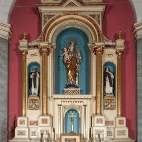 Zdjęcie nr 1: Nastawa ołtarzowa jednokondygnacyjna ze zwieńczeniem, trójosiowa, na cokole. Mensa prostopadłościenna, antepedium podzielone na cztery pola, wydzielone pięcioma kolumienkami, między nimi płyciny w kształcie stojących prostokątów zakończonych łukami półokrągłymi. Na mensie tron wystawienia w formie niszy ujęty parą smukłych kolumienek podtrzymujących szerokie belkowanie; w niszy krucyfiks. Cokół nastawy dekorowany prostokątami z imitacją marmoryzacji. Pierwsza kondygnacja utworzona z trzech arkad wydzielonych kolumnami, oś środkowa wyższa i szersza od bocznych. W polu środkowym figura Matki Boskiej Różańcowej w archiwolcie ujętej kolumienkami, w bocznych figury św. Dominika z lewej i św. Katarzyny Sieneńskiej z prawej strony. Poniżej cokołów postaci plakiety ornamentalne. Kolumny na zdwojonych cokołach, tak jak belkowanie powyżej wyłamane na ich osiach. Cokoły w dekorowane płycinami. Kondygnacja zamknięta belkowaniem przechodzącym w arkadę ponad polem centralnym, archiwolty dekorowane ornamentem roślinnym i geometrycznym. Zwieńczenie w formie leżącego prostokąta, tworzącego wysunięty szczyt, ponad którym krzyż łaciński na cokole ujętym spływami. Pola wypełniają rozety. 
Struktura polichromowana w kolorze kremowym; nisze niebieskie, płyciny i profilowania w kolorze czerwonym oraz szarym, elementy dekoracyjne złocone.
