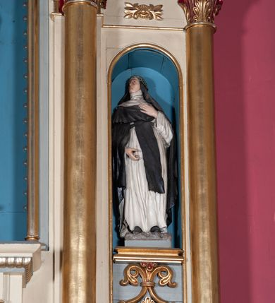 Zdjęcie nr 3: Nastawa ołtarzowa jednokondygnacyjna ze zwieńczeniem, trójosiowa, na cokole. Mensa prostopadłościenna, antepedium podzielone na cztery pola, wydzielone pięcioma kolumienkami, między nimi płyciny w kształcie stojących prostokątów zakończonych łukami półokrągłymi. Na mensie tron wystawienia w formie niszy ujęty parą smukłych kolumienek podtrzymujących szerokie belkowanie; w niszy krucyfiks. Cokół nastawy dekorowany prostokątami z imitacją marmoryzacji. Pierwsza kondygnacja utworzona z trzech arkad wydzielonych kolumnami, oś środkowa wyższa i szersza od bocznych. W polu środkowym figura Matki Boskiej Różańcowej w archiwolcie ujętej kolumienkami, w bocznych figury św. Dominika z lewej i św. Katarzyny Sieneńskiej z prawej strony. Poniżej cokołów postaci plakiety ornamentalne. Kolumny na zdwojonych cokołach, tak jak belkowanie powyżej wyłamane na ich osiach. Cokoły w dekorowane płycinami. Kondygnacja zamknięta belkowaniem przechodzącym w arkadę ponad polem centralnym, archiwolty dekorowane ornamentem roślinnym i geometrycznym. Zwieńczenie w formie leżącego prostokąta, tworzącego wysunięty szczyt, ponad którym krzyż łaciński na cokole ujętym spływami. Pola wypełniają rozety. 
Struktura polichromowana w kolorze kremowym; nisze niebieskie, płyciny i profilowania w kolorze czerwonym oraz szarym, elementy dekoracyjne złocone.
