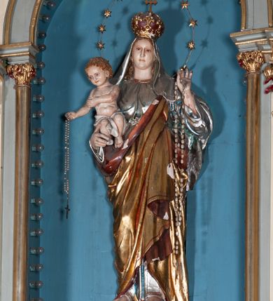 Zdjęcie nr 12: Nastawa ołtarzowa jednokondygnacyjna ze zwieńczeniem, trójosiowa, na cokole. Mensa prostopadłościenna, antepedium podzielone na cztery pola, wydzielone pięcioma kolumienkami, między nimi płyciny w kształcie stojących prostokątów zakończonych łukami półokrągłymi. Na mensie tron wystawienia w formie niszy ujęty parą smukłych kolumienek podtrzymujących szerokie belkowanie; w niszy krucyfiks. Cokół nastawy dekorowany prostokątami z imitacją marmoryzacji. Pierwsza kondygnacja utworzona z trzech arkad wydzielonych kolumnami, oś środkowa wyższa i szersza od bocznych. W polu środkowym figura Matki Boskiej Różańcowej w archiwolcie ujętej kolumienkami, w bocznych figury św. Dominika z lewej i św. Katarzyny Sieneńskiej z prawej strony. Poniżej cokołów postaci plakiety ornamentalne. Kolumny na zdwojonych cokołach, tak jak belkowanie powyżej wyłamane na ich osiach. Cokoły w dekorowane płycinami. Kondygnacja zamknięta belkowaniem przechodzącym w arkadę ponad polem centralnym, archiwolty dekorowane ornamentem roślinnym i geometrycznym. Zwieńczenie w formie leżącego prostokąta, tworzącego wysunięty szczyt, ponad którym krzyż łaciński na cokole ujętym spływami. Pola wypełniają rozety. 
Struktura polichromowana w kolorze kremowym; nisze niebieskie, płyciny i profilowania w kolorze czerwonym oraz szarym, elementy dekoracyjne złocone.
