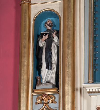 Zdjęcie nr 13: Nastawa ołtarzowa jednokondygnacyjna ze zwieńczeniem, trójosiowa, na cokole. Mensa prostopadłościenna, antepedium podzielone na cztery pola, wydzielone pięcioma kolumienkami, między nimi płyciny w kształcie stojących prostokątów zakończonych łukami półokrągłymi. Na mensie tron wystawienia w formie niszy ujęty parą smukłych kolumienek podtrzymujących szerokie belkowanie; w niszy krucyfiks. Cokół nastawy dekorowany prostokątami z imitacją marmoryzacji. Pierwsza kondygnacja utworzona z trzech arkad wydzielonych kolumnami, oś środkowa wyższa i szersza od bocznych. W polu środkowym figura Matki Boskiej Różańcowej w archiwolcie ujętej kolumienkami, w bocznych figury św. Dominika z lewej i św. Katarzyny Sieneńskiej z prawej strony. Poniżej cokołów postaci plakiety ornamentalne. Kolumny na zdwojonych cokołach, tak jak belkowanie powyżej wyłamane na ich osiach. Cokoły w dekorowane płycinami. Kondygnacja zamknięta belkowaniem przechodzącym w arkadę ponad polem centralnym, archiwolty dekorowane ornamentem roślinnym i geometrycznym. Zwieńczenie w formie leżącego prostokąta, tworzącego wysunięty szczyt, ponad którym krzyż łaciński na cokole ujętym spływami. Pola wypełniają rozety. 
Struktura polichromowana w kolorze kremowym; nisze niebieskie, płyciny i profilowania w kolorze czerwonym oraz szarym, elementy dekoracyjne złocone.
