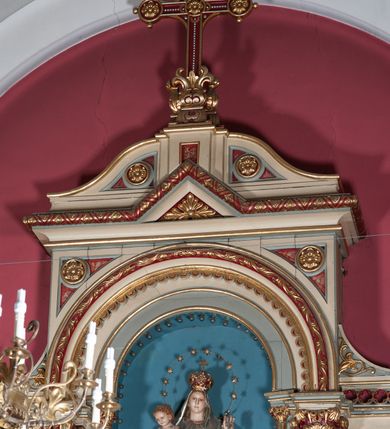 Zdjęcie nr 7: Nastawa ołtarzowa jednokondygnacyjna ze zwieńczeniem, trójosiowa, na cokole. Mensa prostopadłościenna, antepedium podzielone na cztery pola, wydzielone pięcioma kolumienkami, między nimi płyciny w kształcie stojących prostokątów zakończonych łukami półokrągłymi. Na mensie tron wystawienia w formie niszy ujęty parą smukłych kolumienek podtrzymujących szerokie belkowanie; w niszy krucyfiks. Cokół nastawy dekorowany prostokątami z imitacją marmoryzacji. Pierwsza kondygnacja utworzona z trzech arkad wydzielonych kolumnami, oś środkowa wyższa i szersza od bocznych. W polu środkowym figura Matki Boskiej Różańcowej w archiwolcie ujętej kolumienkami, w bocznych figury św. Dominika z lewej i św. Katarzyny Sieneńskiej z prawej strony. Poniżej cokołów postaci plakiety ornamentalne. Kolumny na zdwojonych cokołach, tak jak belkowanie powyżej wyłamane na ich osiach. Cokoły w dekorowane płycinami. Kondygnacja zamknięta belkowaniem przechodzącym w arkadę ponad polem centralnym, archiwolty dekorowane ornamentem roślinnym i geometrycznym. Zwieńczenie w formie leżącego prostokąta, tworzącego wysunięty szczyt, ponad którym krzyż łaciński na cokole ujętym spływami. Pola wypełniają rozety. 
Struktura polichromowana w kolorze kremowym; nisze niebieskie, płyciny i profilowania w kolorze czerwonym oraz szarym, elementy dekoracyjne złocone.
