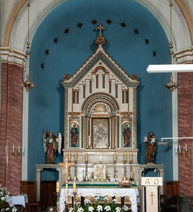 Zdjęcie nr 2: Ołtarz architektoniczny, jednokondygnacyjny, trójosiowy ze zwieńczeniem i bramkami, ustawiony na cokole. Mensa marmurowa z portatylem. Antepedium w formie wydłużonego, leżącego prostokąta. Ujęte w profilowaną ramę, podzielone na trzy części. Partia środkowa kwadratowa, w niej medalion z płaskorzeźbionym przedstawieniem gorejącego serca na tle skrzyżowanego krzyża i kotwicy. W partiach bocznych płaskorzeźbiony motyw maswerku. Na mensie prostopadłościenne tabernakulum z drzwiczkami dekorowanymi motywem silnie stylizowanych winnych gron, ustawione na cokole przerywanym trzema plakietami roślinnymi. Tabernakulum z dwóch stron podtrzymują stylizowane anioły. Pole środkowe nastawy ołtarza w formie uskokowego portalu zamkniętego półokrągłym łukiem z tympanonem. Dwie wewnętrzne archiwolty podtrzymywane przez półkolumny z kapitelami kompozytowymi, zewnętrzna przez pilastry. Portal flankują dwie nisze, zwieńczone łukiem nadwieszonym. Pierwszą kondygnację zamyka pas fryzu. W polu zwieńczenia ponad łukiem portalu rozchodzi się stopniowo pięć par kolumn o kostkowych kapitelach, które w partii wieńczącej podtrzymują profilowany łuk nadwieszony. Zwieńczenie zamknięte trójkątną linią belkowania, z pasem stopniowo spływających wolut, zakończone krzyżem. Cokół dekorowany płycinami z perełkowaniem, zakończony gzymsem z motywem wolich oczu. Poszczególne elementy niszy dekorowane różnorodnym ornamentem o charakterze geometryczno-roślinnym. W polu środkowym obraz Matki Boskiej z Dzieciątkiem w srebrnej sukience (Matki Boskiej Lisieckiej). W tympanonie płaskorzeźbione przedstawienie imienia Boga ujętego w trójkąt w glorii promienistej, w otoczeniu putt pośród obłoków. Nisze flankujące portal zwieńczone są płaskorzeźbionymi przedstawieniami centralnych świątyń kopułowych. W niszach płaskorzeźby św. Piotra po lewej i św. Pawła po prawej stronie. Fryz zamykający kondygnację z motywem palmet, w miejscu przecięcia z opaską portalu – uskrzydlone główki anielskie. W partii zwieńczenia, w przestrzeniach ponad kolumnami rozety. Ostatnia para kolumn ujęta w pionowe pasy imitujące zwinięty sznur. Łuk nadwieszony dekorowany ornamentem roślinnym. Cały ołtarz ujęty w pasy z dekoracją roślinną i motywem sznura. Wieńczące belkowanie z dekoracją geometryczną i rozetami, ujęte w woluty z mięsistego akantu. Podstawę dla krzyża tworzy akant z motywem palmety i perełkowania. Ołtarz flankują dwie bramki, na których stoją figury św. Michała Archanioła po lewej i św. Józefa po prawej stronie. 
Struktura w kolorze naturalnego kamienia – kremowa, profile w odcieniach niebieskiego, detale i ornamenty złocone. 
