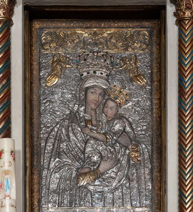Zdjęcie nr 23: Ołtarz architektoniczny, jednokondygnacyjny, trójosiowy ze zwieńczeniem i bramkami, ustawiony na cokole. Mensa marmurowa z portatylem. Antepedium w formie wydłużonego, leżącego prostokąta. Ujęte w profilowaną ramę, podzielone na trzy części. Partia środkowa kwadratowa, w niej medalion z płaskorzeźbionym przedstawieniem gorejącego serca na tle skrzyżowanego krzyża i kotwicy. W partiach bocznych płaskorzeźbiony motyw maswerku. Na mensie prostopadłościenne tabernakulum z drzwiczkami dekorowanymi motywem silnie stylizowanych winnych gron, ustawione na cokole przerywanym trzema plakietami roślinnymi. Tabernakulum z dwóch stron podtrzymują stylizowane anioły. Pole środkowe nastawy ołtarza w formie uskokowego portalu zamkniętego półokrągłym łukiem z tympanonem. Dwie wewnętrzne archiwolty podtrzymywane przez półkolumny z kapitelami kompozytowymi, zewnętrzna przez pilastry. Portal flankują dwie nisze, zwieńczone łukiem nadwieszonym. Pierwszą kondygnację zamyka pas fryzu. W polu zwieńczenia ponad łukiem portalu rozchodzi się stopniowo pięć par kolumn o kostkowych kapitelach, które w partii wieńczącej podtrzymują profilowany łuk nadwieszony. Zwieńczenie zamknięte trójkątną linią belkowania, z pasem stopniowo spływających wolut, zakończone krzyżem. Cokół dekorowany płycinami z perełkowaniem, zakończony gzymsem z motywem wolich oczu. Poszczególne elementy niszy dekorowane różnorodnym ornamentem o charakterze geometryczno-roślinnym. W polu środkowym obraz Matki Boskiej z Dzieciątkiem w srebrnej sukience (Matki Boskiej Lisieckiej). W tympanonie płaskorzeźbione przedstawienie imienia Boga ujętego w trójkąt w glorii promienistej, w otoczeniu putt pośród obłoków. Nisze flankujące portal zwieńczone są płaskorzeźbionymi przedstawieniami centralnych świątyń kopułowych. W niszach płaskorzeźby św. Piotra po lewej i św. Pawła po prawej stronie. Fryz zamykający kondygnację z motywem palmet, w miejscu przecięcia z opaską portalu – uskrzydlone główki anielskie. W partii zwieńczenia, w przestrzeniach ponad kolumnami rozety. Ostatnia para kolumn ujęta w pionowe pasy imitujące zwinięty sznur. Łuk nadwieszony dekorowany ornamentem roślinnym. Cały ołtarz ujęty w pasy z dekoracją roślinną i motywem sznura. Wieńczące belkowanie z dekoracją geometryczną i rozetami, ujęte w woluty z mięsistego akantu. Podstawę dla krzyża tworzy akant z motywem palmety i perełkowania. Ołtarz flankują dwie bramki, na których stoją figury św. Michała Archanioła po lewej i św. Józefa po prawej stronie. 
Struktura w kolorze naturalnego kamienia – kremowa, profile w odcieniach niebieskiego, detale i ornamenty złocone. 

