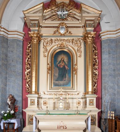 Zdjęcie nr 1: Ołtarz przyścienny, architektoniczny, jednoosiowy, jednokondygnacyjny, ze zwieńczeniem, na podwójnym cokole. Mensa w typie sarkofagowym; antepedium dekorowane monogramem IHS. Na mensie tabernakulum na rzucie zbliżonym do kwadratu, na profilowanej podstawie. Na licu drzwi w kształcie stojącego prostokąta zamkniętego łukiem półkolistym, ujęte kolumienkami, nad którymi gzyms i szczyt zamknięty łukiem nadwieszonym, wypełniony palmetą. Tabernakulum wieńczy krucyfiks. Oś środkowa nastawy flankowana parą kolumn o kapitelach kompozytowych, ustawionych przed licem ołtarza. Cokoły kolumn dekorowane płycinami z symetryczną dekoracją z wici. Podpory dźwigają pełne, wyłamane wielokrotnie belkowanie oraz odpowiadający ich ułożeniu wyłamany, trójkątny przyczółek. Na jego środku płaskorzeźba przedstawiająca gołębicę Ducha Świętego na tle obłoków i glorii. Między fryzem i gzumsem rząd kostkowania. W polu środkowym we wnęce w kształcie stojącego prostokąta zamkniętego łukiem półkolistym obraz Najświętszego Serca Jezusa w profilowanej ramie dekorowanej w kluczu i w połowie wysokości plakietami ornamentalnymi. W polach pod i nad obrazem wypełnienie z wici roślinnej, na fryzie belkowania kartusz z inskrypcją „SOLI DEO”. Kondygnację ujmują ażurowe uszaki utworzone z wici akantowej. Zwieńczenie w formie krzyża łacińskiego ustawionego na cokole ujętym wolutami. Struktura polichromowana na kremowo, fryzy i płyciny na szaro, detale, kolumny i ornamentyka złocone. 