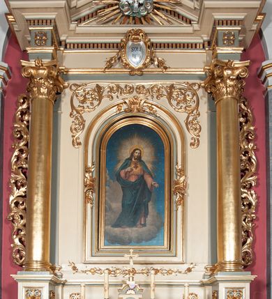 Zdjęcie nr 7: Ołtarz przyścienny, architektoniczny, jednoosiowy, jednokondygnacyjny, ze zwieńczeniem, na podwójnym cokole. Mensa w typie sarkofagowym; antepedium dekorowane monogramem IHS. Na mensie tabernakulum na rzucie zbliżonym do kwadratu, na profilowanej podstawie. Na licu drzwi w kształcie stojącego prostokąta zamkniętego łukiem półkolistym, ujęte kolumienkami, nad którymi gzyms i szczyt zamknięty łukiem nadwieszonym, wypełniony palmetą. Tabernakulum wieńczy krucyfiks. Oś środkowa nastawy flankowana parą kolumn o kapitelach kompozytowych, ustawionych przed licem ołtarza. Cokoły kolumn dekorowane płycinami z symetryczną dekoracją z wici. Podpory dźwigają pełne, wyłamane wielokrotnie belkowanie oraz odpowiadający ich ułożeniu wyłamany, trójkątny przyczółek. Na jego środku płaskorzeźba przedstawiająca gołębicę Ducha Świętego na tle obłoków i glorii. Między fryzem i gzumsem rząd kostkowania. W polu środkowym we wnęce w kształcie stojącego prostokąta zamkniętego łukiem półkolistym obraz Najświętszego Serca Jezusa w profilowanej ramie dekorowanej w kluczu i w połowie wysokości plakietami ornamentalnymi. W polach pod i nad obrazem wypełnienie z wici roślinnej, na fryzie belkowania kartusz z inskrypcją „SOLI DEO”. Kondygnację ujmują ażurowe uszaki utworzone z wici akantowej. Zwieńczenie w formie krzyża łacińskiego ustawionego na cokole ujętym wolutami. Struktura polichromowana na kremowo, fryzy i płyciny na szaro, detale, kolumny i ornamentyka złocone. 
