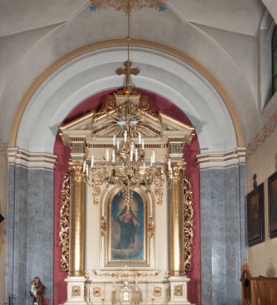Zdjęcie nr 6: Ołtarz przyścienny, architektoniczny, jednoosiowy, jednokondygnacyjny, ze zwieńczeniem, na podwójnym cokole. Mensa w typie sarkofagowym; antepedium dekorowane monogramem IHS. Na mensie tabernakulum na rzucie zbliżonym do kwadratu, na profilowanej podstawie. Na licu drzwi w kształcie stojącego prostokąta zamkniętego łukiem półkolistym, ujęte kolumienkami, nad którymi gzyms i szczyt zamknięty łukiem nadwieszonym, wypełniony palmetą. Tabernakulum wieńczy krucyfiks. Oś środkowa nastawy flankowana parą kolumn o kapitelach kompozytowych, ustawionych przed licem ołtarza. Cokoły kolumn dekorowane płycinami z symetryczną dekoracją z wici. Podpory dźwigają pełne, wyłamane wielokrotnie belkowanie oraz odpowiadający ich ułożeniu wyłamany, trójkątny przyczółek. Na jego środku płaskorzeźba przedstawiająca gołębicę Ducha Świętego na tle obłoków i glorii. Między fryzem i gzumsem rząd kostkowania. W polu środkowym we wnęce w kształcie stojącego prostokąta zamkniętego łukiem półkolistym obraz Najświętszego Serca Jezusa w profilowanej ramie dekorowanej w kluczu i w połowie wysokości plakietami ornamentalnymi. W polach pod i nad obrazem wypełnienie z wici roślinnej, na fryzie belkowania kartusz z inskrypcją „SOLI DEO”. Kondygnację ujmują ażurowe uszaki utworzone z wici akantowej. Zwieńczenie w formie krzyża łacińskiego ustawionego na cokole ujętym wolutami. Struktura polichromowana na kremowo, fryzy i płyciny na szaro, detale, kolumny i ornamentyka złocone. 