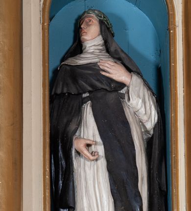 Zdjęcie nr 1: Rzeźba pełnoplastyczna, całopostaciowa, wydrążona od tyłu, na cokole.  Święta Katarzyna została ukazana frontalnie, z głową zwróconą w prawo. Prawą rękę ma opuszczoną, lewą składa na piersi w subtelnym geście. Święta ma owalną twarz o ostrych rysach, szeroko ptwarte oczy, wzrok uniesiony, wąskie brwi, prosty nos oraz wąskie, rozchylone usta. Jest ubrana w habit dominikański: białą tunikę przewiązaną czarnym pasem, czarny szkaplerz oraz długą czarną kapę i krótką pelerynkę, białą podwikę, na głowie ma welon i srebrną koronę cierniową. 
Polichromia w partiach ciała naturalistyczna.
