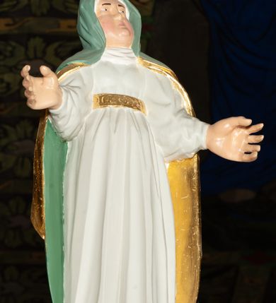 Zdjęcie nr 9: Trójfigurowa grupa Ukrzyżowania, rzeźby pełne. W środku znajduje się krucyfiks z postacią umarłego Chrystusa przybitego trzema gwoździami do krzyża. Chrystus w lekkim zwisie, o szeroko rozłożonych ramionach, bezwładny, głowa opuszczona na prawe ramię. Twarz szczupła, owalna, o prostym nosie, dużych oczach i na wpół otwartych ustach, okolona zarostem. Włosy w postaci delikatnych fal opadają na plecy i prawe ramię. Na głowie korona cierniowa. Ciało o wyraźnie zarysowanej anatomii. Perizonium w formie tkaniny przewiązanej na boku i odsłaniającej prawe biodro, z dłuższym brzegiem zwisającym po prawej stronie. Draperia gęsto fałdowana, o miękkich załamaniach materiału. Na szczycie pionowej belki titulus w formie banderoli z napisem „IN/RI”. Figura Matki Boskiej ustawiona po lewej stronie, zwrócona lekko w stronę krzyża, z głową uniesioną w kierunku Chrystusa i uniesionymi rękami. Twarz podłużna, niemal bez cech indywidualnych. Ubrana w długą białą suknię ze złotym paskiem, zielony płaszcz ze złotym podbiciem okrywający głowę, ramiona i plecy. Figura Marii Magdaleny po prawej stronie. Święta klęczy odwrócona od krzyża, z uniesioną głową i rozłożonymi rękami. Twarz młoda, owalna o słabo zindywidualizowanych rysach, włosy w postaci loków opadają na plecy. Jest ubrana w różową suknię ze złotym pasem oraz niebieski płaszcz ze złotym podbiciem. Polichromia w partiach ciała naturalistyczna. 