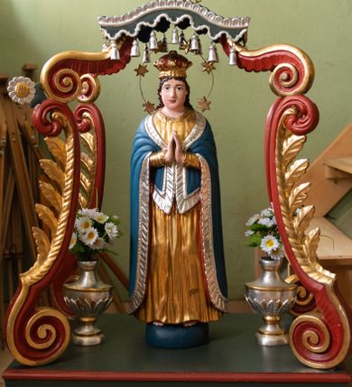 Zdjęcie nr 1: Feretron na profilowanej, prostopadłościennej podstawie z przedstawieniem Maki Boskiej Niepokalanej. Rzeźba pełna została ustawiona na cokole imitującym połowę globu. Maria została ukazana całopostaciowo, frontalnie, z dłońmi złożonymi w geście modlitwy. Twarz ma owalną, o pełnych policzkach i szeroko otwartych, ciemnych oczach; długie, ciemne włosy, opadają jej na plecy. Maria jest ubrana w złotą suknię, o wąskich rękawach i narzucony na ramiona niebieski płaszcz ze srebrną lamówką; na głowie ma koronę, wokół głowy nimb złożony z sześciu gwiazd przytrzymywanych drucikiem. Figura została ujęta rzeźbionymi  wolutami dekorowanymi liśćmi, podtrzymującymi baldachim z lambrekinem zwieńczony monogramem „MARYA” w otoczeniu glorii. Polichromia naturalistyczna w odsłoniętych partiach ciała; podstawa zielono-czerwona, woluty czerwone, baldachim szary, profile i ornamenty złocone i srebrzone. 