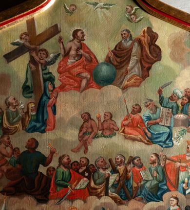 Zdjęcie nr 2: Obraz w formie stojącego prostokąta o falistym, wklęsło-wypukłym zamknięciu, ujęty profilowaną, złoconą ramą. Przedstawienie wielopostaciowe, na tle chmur, podzielone na strefy. W dolnej części wśród obłoków czterej ojcowie Kościoła i czterej ewangeliści z atrybutami, wyżej apostołowie, król Dawid i św. Barbara, w trzeciej strefie z lewej św. Józef, Matka Boska i św. Jan, pod krzyżem, pośrodku Adam i Ewa, z prawej Mojżesz z dekalogiem i postacie starotestamentowe. Najwyżej Bóg Ojciec, Chrystus z kulą świata i gołębica Ducha Świętego. Między wymienionymi najważniejszymi postacie mniej znaczących świetych, m.in. św. Floriana, św. Katarzyny ALeksandryjskiej, św. Jana Chrzciciela, św. Joachima, św. Anny. Kolorystyka intensywna, silne kontrasty, płaska plama barwna.