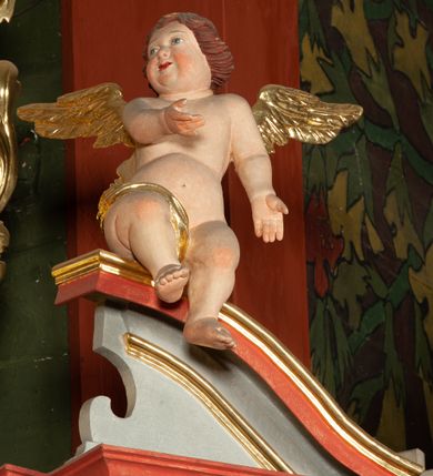 Zdjęcie nr 5: Ołtarz architektoniczny, jednokondygnacyjny, jednoosiowy, ze zwieńczeniem i drewnianą, sarkofagową mensą z kamiennym portatylem. Na mensie ołtarza kremowe tabernakulum w formie prostopadłościennej szafki, ujęte parą korynckich, złoconych półkolumienek, stojących na wyłamującym się, zdwojonym cokoliku, wspierających silnie wysunięty gzyms wieńczący. Drzwiczki w kształcie stojącego prostokąta, z prostokątną płyciną zwieńczoną łukiem półkolistym, zdobioną płaskorzeźbionym motywem kielicha, hostii, kłosów zboża i winnych gron.  Retabulum na cokole, ujęte parą pilastrów korynckich, z kanelurowaniem do połowy trzonu i parą filarów, na tle których ustawiona jest para kolumn akantowych o spiralnie skręconych trzonach. Podpory wspierają wyłamujące się ponad nimi belkowanie o wysuniętym gzymsie. Zwieńczenie w formie stojącego owalu ujętego ażurową, akantową ramą, flankowane przerwanym, wklęsło wypukłym przyczółkiem. Dolne naroża antepedium zdobione motywem lwiej łapy ujętej parą wolut, z liściem akantu w zwieńczeniu. Pola cokołu, dolna partia pola środkowego i pola wewnątrz wnęki, oraz fryz retabulum zdobiony motywem wici akantowej. Na trzonach kolumn retabulum spiralnie oplatająca ją wić roślinna. Cześć środkowa retabulum ujęta parą ażurowych, akantowych uszaków. Pole środkowe w formie wnęki w kształcie stojącego prostokąta z przedstawieniem Matki Boskiej Nieustającej Pomocy oraz Niepokalanego Poczęcia Najświętszej Marii Panny na zasuwie. W zwieńczeniu pole obrazowe w kształcie stojącego owalu z przedstawieniem Veraicon. Na gzymsie przyczółka para siedzących aniołków. Kolorystyka struktury ołtarza w odcieniach szarości i czerwieni; ornamentyka i fragmenty detali architektonicznych złocone.  