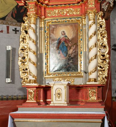 Zdjęcie nr 6: Ołtarz architektoniczny, jednokondygnacyjny, jednoosiowy, ze zwieńczeniem i drewnianą, sarkofagową mensą z kamiennym portatylem. Na mensie ołtarza kremowe tabernakulum w formie prostopadłościennej szafki, ujęte parą korynckich, złoconych półkolumienek, stojących na wyłamującym się, zdwojonym cokoliku, wspierających silnie wysunięty gzyms wieńczący. Drzwiczki w kształcie stojącego prostokąta, z prostokątną płyciną zwieńczoną łukiem półkolistym, zdobioną płaskorzeźbionym motywem kielicha, hostii, kłosów zboża i winnych gron.  Retabulum na cokole, ujęte parą pilastrów korynckich, z kanelurowaniem do połowy trzonu i parą filarów, na tle których ustawiona jest para kolumn akantowych o spiralnie skręconych trzonach. Podpory wspierają wyłamujące się ponad nimi belkowanie o wysuniętym gzymsie. Zwieńczenie w formie stojącego owalu ujętego ażurową, akantową ramą, flankowane przerwanym, wklęsło wypukłym przyczółkiem. Dolne naroża antepedium zdobione motywem lwiej łapy ujętej parą wolut, z liściem akantu w zwieńczeniu. Pola cokołu, dolna partia pola środkowego i pola wewnątrz wnęki, oraz fryz retabulum zdobiony motywem wici akantowej. Na trzonach kolumn retabulum spiralnie oplatająca ją wić roślinna. Cześć środkowa retabulum ujęta parą ażurowych, akantowych uszaków. Pole środkowe w formie wnęki w kształcie stojącego prostokąta z przedstawieniem Matki Boskiej Nieustającej Pomocy oraz Niepokalanego Poczęcia Najświętszej Marii Panny na zasuwie. W zwieńczeniu pole obrazowe w kształcie stojącego owalu z przedstawieniem Veraicon. Na gzymsie przyczółka para siedzących aniołków. Kolorystyka struktury ołtarza w odcieniach szarości i czerwieni; ornamentyka i fragmenty detali architektonicznych złocone.  