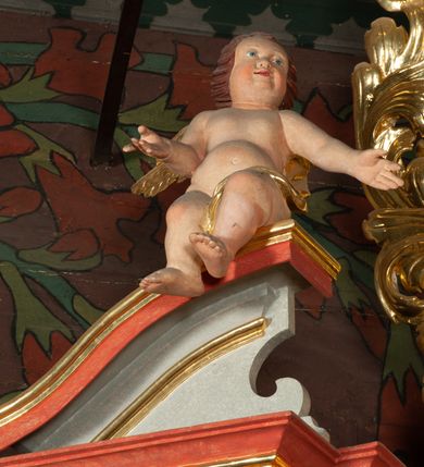 Zdjęcie nr 4: Ołtarz architektoniczny, jednokondygnacyjny, jednoosiowy, ze zwieńczeniem i drewnianą, sarkofagową mensą z kamiennym portatylem. Na mensie ołtarza kremowe tabernakulum w formie prostopadłościennej szafki, ujęte parą korynckich, złoconych półkolumienek, stojących na wyłamującym się, zdwojonym cokoliku, wspierających silnie wysunięty gzyms wieńczący. Drzwiczki w kształcie stojącego prostokąta, z prostokątną płyciną zwieńczoną łukiem półkolistym, zdobioną płaskorzeźbionym motywem kielicha, hostii, kłosów zboża i winnych gron.  Retabulum na cokole, ujęte parą pilastrów korynckich, z kanelurowaniem do połowy trzonu i parą filarów, na tle których ustawiona jest para kolumn akantowych o spiralnie skręconych trzonach. Podpory wspierają wyłamujące się ponad nimi belkowanie o wysuniętym gzymsie. Zwieńczenie w formie stojącego owalu ujętego ażurową, akantową ramą, flankowane przerwanym, wklęsło wypukłym przyczółkiem. Dolne naroża antepedium zdobione motywem lwiej łapy ujętej parą wolut, z liściem akantu w zwieńczeniu. Pola cokołu, dolna partia pola środkowego i pola wewnątrz wnęki, oraz fryz retabulum zdobiony motywem wici akantowej. Na trzonach kolumn retabulum spiralnie oplatająca ją wić roślinna. Cześć środkowa retabulum ujęta parą ażurowych, akantowych uszaków. Pole środkowe w formie wnęki w kształcie stojącego prostokąta z przedstawieniem Matki Boskiej Nieustającej Pomocy oraz Niepokalanego Poczęcia Najświętszej Marii Panny na zasuwie. W zwieńczeniu pole obrazowe w kształcie stojącego owalu z przedstawieniem Veraicon. Na gzymsie przyczółka para siedzących aniołków. Kolorystyka struktury ołtarza w odcieniach szarości i czerwieni; ornamentyka i fragmenty detali architektonicznych złocone.  