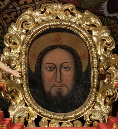 Zdjęcie nr 12: Ołtarz architektoniczny, jednokondygnacyjny, jednoosiowy, ze zwieńczeniem i drewnianą, sarkofagową mensą z kamiennym portatylem. Na mensie ołtarza kremowe tabernakulum w formie prostopadłościennej szafki, ujęte parą korynckich, złoconych półkolumienek, stojących na wyłamującym się, zdwojonym cokoliku, wspierających silnie wysunięty gzyms wieńczący. Drzwiczki w kształcie stojącego prostokąta, z prostokątną płyciną zwieńczoną łukiem półkolistym, zdobioną płaskorzeźbionym motywem kielicha, hostii, kłosów zboża i winnych gron.  Retabulum na cokole, ujęte parą pilastrów korynckich, z kanelurowaniem do połowy trzonu i parą filarów, na tle których ustawiona jest para kolumn akantowych o spiralnie skręconych trzonach. Podpory wspierają wyłamujące się ponad nimi belkowanie o wysuniętym gzymsie. Zwieńczenie w formie stojącego owalu ujętego ażurową, akantową ramą, flankowane przerwanym, wklęsło wypukłym przyczółkiem. Dolne naroża antepedium zdobione motywem lwiej łapy ujętej parą wolut, z liściem akantu w zwieńczeniu. Pola cokołu, dolna partia pola środkowego i pola wewnątrz wnęki, oraz fryz retabulum zdobiony motywem wici akantowej. Na trzonach kolumn retabulum spiralnie oplatająca ją wić roślinna. Cześć środkowa retabulum ujęta parą ażurowych, akantowych uszaków. Pole środkowe w formie wnęki w kształcie stojącego prostokąta z przedstawieniem Matki Boskiej Nieustającej Pomocy oraz Niepokalanego Poczęcia Najświętszej Marii Panny na zasuwie. W zwieńczeniu pole obrazowe w kształcie stojącego owalu z przedstawieniem Veraicon. Na gzymsie przyczółka para siedzących aniołków. Kolorystyka struktury ołtarza w odcieniach szarości i czerwieni; ornamentyka i fragmenty detali architektonicznych złocone.  