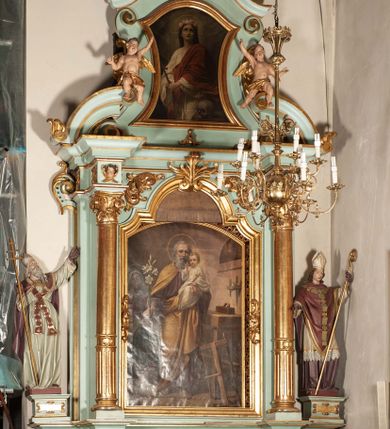Zdjęcie nr 1: Nastawa architektoniczna, jednoosiowa, jednokondygnacyjna ze zwieńczeniem. Ołtarz drewniany, prostopadłościenny, z drewnianą mensą, ustawiony na profilowanym cokole. Ścianka frontowa ujęta pilastrami z płycinami w partii trzonów z akantem. W polu dwie płyciny o fantazyjnej formie wypełnione stylizowanym ornamentem akantowym, flankujące medalion z inicjałami „MS”. Ścianki boczne dekorowane płycinami. 
Na ołtarzu ustawione tabernakulum w formie drewnianej skrzynki, na cokole, flankowanej spływami wolutowymi, zwieńczonej szczytem zamkniętym łukowatym fragmentem gzymsu z płyciną i uskrzydloną główką anielską w polu. Drzwiczki w kształciestojącego prostokąta zamkniętego łukiem falistym, ujęte profilowaną ramą z przedstawieniem kielicha z hostią. 
Nastawa na cokole z wyodrębnionymi dwoma prostopadłościanami i dwoma skrajnymi konsolami, dekorowanym płycinami ze stylizowanym ornamentem. Retabulum ujęte parą kolumn o trzonach kanelowanych w jednej trzeciej wysokości, podtrzymujących belkowanie o architrawie i fryzie przerwanym nad polem środkowym. Na belkowaniu fragmenty przerwanego, półkolistego przyczółka z siedzącymi puttami. Niemal całe pole główne wypełnione wnęką w formie stojącego prostokąta zamkniętego łukiem półkolistym nadwieszonym, z uskokiem, w profilowanej ramie, z obrazami komunii anielskiej św. Stanisława Kostki i św. Józefa na zasuwie. Na konsolach, po bokach nastawy ustawione figury św. Wojciecha i św. Stanisława. Zwieńczenie w formie zbliżonej do stojącego prostokąta, ujętego spływami wolutowymi, zamkniętego dwiema stykającymi się wolutami oraz dwiema uskrzydlonymi główkami anielskimi w glorii promienistej. W polu obraz św. Rozalii w kształcie zbliżonym do zwieńczenia, ujęty profilowaną ramą. Struktura polichromowana w kolorze seledynowym, kolumny, profile i ornamentyka złocone. 


