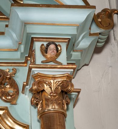 Zdjęcie nr 10: Nastawa architektoniczna, jednoosiowa, jednokondygnacyjna ze zwieńczeniem. Ołtarz drewniany, prostopadłościenny, z drewnianą mensą, ustawiony na profilowanym cokole. Ścianka frontowa ujęta pilastrami z płycinami w partii trzonów z akantem. W polu dwie płyciny o fantazyjnej formie wypełnione stylizowanym ornamentem akantowym, flankujące medalion z inicjałami „MS”. Ścianki boczne dekorowane płycinami. 
Na ołtarzu ustawione tabernakulum w formie drewnianej skrzynki, na cokole, flankowanej spływami wolutowymi, zwieńczonej szczytem zamkniętym łukowatym fragmentem gzymsu z płyciną i uskrzydloną główką anielską w polu. Drzwiczki w kształciestojącego prostokąta zamkniętego łukiem falistym, ujęte profilowaną ramą z przedstawieniem kielicha z hostią. 
Nastawa na cokole z wyodrębnionymi dwoma prostopadłościanami i dwoma skrajnymi konsolami, dekorowanym płycinami ze stylizowanym ornamentem. Retabulum ujęte parą kolumn o trzonach kanelowanych w jednej trzeciej wysokości, podtrzymujących belkowanie o architrawie i fryzie przerwanym nad polem środkowym. Na belkowaniu fragmenty przerwanego, półkolistego przyczółka z siedzącymi puttami. Niemal całe pole główne wypełnione wnęką w formie stojącego prostokąta zamkniętego łukiem półkolistym nadwieszonym, z uskokiem, w profilowanej ramie, z obrazami komunii anielskiej św. Stanisława Kostki i św. Józefa na zasuwie. Na konsolach, po bokach nastawy ustawione figury św. Wojciecha i św. Stanisława. Zwieńczenie w formie zbliżonej do stojącego prostokąta, ujętego spływami wolutowymi, zamkniętego dwiema stykającymi się wolutami oraz dwiema uskrzydlonymi główkami anielskimi w glorii promienistej. W polu obraz św. Rozalii w kształcie zbliżonym do zwieńczenia, ujęty profilowaną ramą. Struktura polichromowana w kolorze seledynowym, kolumny, profile i ornamentyka złocone. 


