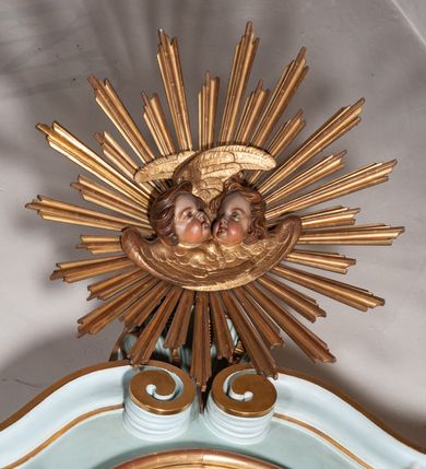 Zdjęcie nr 6: Nastawa architektoniczna, jednoosiowa, jednokondygnacyjna ze zwieńczeniem. Ołtarz drewniany, prostopadłościenny, z drewnianą mensą, ustawiony na profilowanym cokole. Ścianka frontowa ujęta pilastrami z płycinami w partii trzonów z akantem. W polu dwie płyciny o fantazyjnej formie wypełnione stylizowanym ornamentem akantowym, flankujące medalion z inicjałami „MS”. Ścianki boczne dekorowane płycinami. 
Na ołtarzu ustawione tabernakulum w formie drewnianej skrzynki, na cokole, flankowanej spływami wolutowymi, zwieńczonej szczytem zamkniętym łukowatym fragmentem gzymsu z płyciną i uskrzydloną główką anielską w polu. Drzwiczki w kształciestojącego prostokąta zamkniętego łukiem falistym, ujęte profilowaną ramą z przedstawieniem kielicha z hostią. 
Nastawa na cokole z wyodrębnionymi dwoma prostopadłościanami i dwoma skrajnymi konsolami, dekorowanym płycinami ze stylizowanym ornamentem. Retabulum ujęte parą kolumn o trzonach kanelowanych w jednej trzeciej wysokości, podtrzymujących belkowanie o architrawie i fryzie przerwanym nad polem środkowym. Na belkowaniu fragmenty przerwanego, półkolistego przyczółka z siedzącymi puttami. Niemal całe pole główne wypełnione wnęką w formie stojącego prostokąta zamkniętego łukiem półkolistym nadwieszonym, z uskokiem, w profilowanej ramie, z obrazami komunii anielskiej św. Stanisława Kostki i św. Józefa na zasuwie. Na konsolach, po bokach nastawy ustawione figury św. Wojciecha i św. Stanisława. Zwieńczenie w formie zbliżonej do stojącego prostokąta, ujętego spływami wolutowymi, zamkniętego dwiema stykającymi się wolutami oraz dwiema uskrzydlonymi główkami anielskimi w glorii promienistej. W polu obraz św. Rozalii w kształcie zbliżonym do zwieńczenia, ujęty profilowaną ramą. Struktura polichromowana w kolorze seledynowym, kolumny, profile i ornamentyka złocone. 


