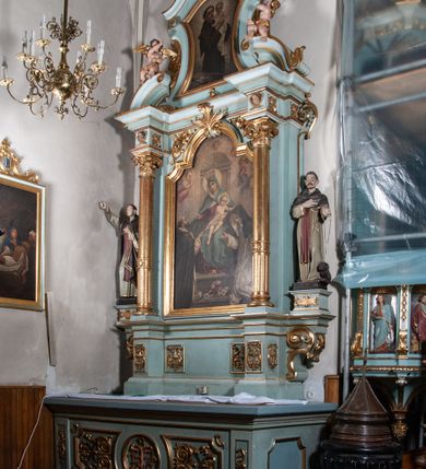Zdjęcie nr 2: Nastawa architektoniczna, jednoosiowa, jednokondygnacyjna ze zwieńczeniem. Ołtarz drewniany, prostopadłościenny, z drewnianą mensą, ustawiony na profilowanym cokole. Ścianka frontowa ujęta lizenami z płycinami w partii trzonów z akantem. W polu dwie płyciny o fantazyjnej formie wypełnione stylizowanym ornamentem akantowym, flankujące medalion z monogramem Marii. Ścianki boczne dekorowane płycinami. 
Nastawa na cokole z wyodrębnionymi dwoma prostopadłościanami i dwoma skrajnymi konsolami, dekorowana płycinami ze stylizowanym ornamentem. Retabulum ujęte parą kolumn o trzonach kanelowanych w jednej trzeciej wysokości, podtrzymującymi belkowanie o architrawie i fryzie przerwanym nad polem środkowym. Na belkowaniu fragmenty przerwanego, półkolistego przyczółka z siedzącymi puttami. Niemal całe pole główne wypełnione wnęką w formie stojącego prostokąta zamkniętego łukiem półkolistym nadwieszonym, z uskokiem, w profilowanej ramie, z mniejszym obrazem Matki Boskiej Śnieżnej w osobnej ramie. Na konsolach, po bokach nastawy ustawione figury św. Jacka i bł. Czesława. Zwieńczenie w formie zbliżonej do stojącego prostokąta, ujętego spływami wolutowymi, zamkniętego dwiema stykającymi się wolutami oraz dwiema uskrzydlonymi główkami anielskimi w glorii promienistej. W polu obraz św. Antoniego Padewskiego w formie zbliżonej do zwieńczenia, ujęty profilowaną ramą. Struktura polichromowana w kolorze seledynowym, kolumny, profile i ornamentyka złocone. 
