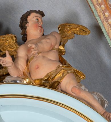 Zdjęcie nr 41: Nastawa architektoniczna, jednoosiowa, jednokondygnacyjna, ustawiona na wysokim cokole. 
Ołtarz drewniany, prostopadłościenny. Na nim tabernakulum z tronem wystawienia. Tabernakulum w formie drewnianej, prostopadłościennej skrzynki, obitej blachą, o wypukłej ściance frontowej, zamkniętej profilowanym gzymsem. Drzwiczki w formie stojącego prostokąta zamkniętego łukiem półkolistym, obwiedzione ramą, z wizerunkiem baranka z krzyżem, leżącego na księdze z pieczęciami, w glorii. Tabernakulum w drewnianej obudowie, wpisane w wysoki cokół, na nim tron wystawienia w formie obrotowej niszy w kształcie stojącego prostokąta, z podwieszoną draperią. Nisza flankowana parą pilastrów, przechodzących w spływy wolutowe, na których siedzą putta. Pilastry dźwigają pełne belkowanie, wyłamane na ich osi, częściowo przerwane przez niszę. Pilastry dekorowane uskrzydlonymi główkami anielskimi oraz snopkiem zboża i kiściami winogron. Cały tron wystawienia dekorowany rocaille'm. 
Nastawa ujęta dwiema parami kolumn o kapitelach kompozytowych, dźwigających pełne belkowanie, wyłamane pomiędzy nimi, przerwane nad polem środkowym. Na belkowaniu fragmenty przerwanego, półkolistego przyczółka, na których leżą putta. Całe pole środkowe wypełnia wnęka w formie stojącego prostokąta zamkniętego łukiem półkolistym, ujęta profilowaną ramą, z figurą Chrystusa Ukrzyżowanego. Nad łukiem wnęki, pomiędzy obłokami, gołębica Ducha Świętego w glorii promienistej. Pomiędzy kolumnami płyciny z uskrzydlonymi główkami anielskimi na obłokach, rocaille oraz figury św.  Jana Ewangelisty i Matki Boskiej na rocaille'owych wspornikach. Kondygnacja ujęta uszami utworzonymi z rocaille'u. Nastawa zwieńczona rzeźbą tronującego Boga Ojca z globem i berłem, pośród obłoków i uskrzydlonych główek anielskich, w glorii promienistej. 
Struktura polichromowana w kolorze błękitnym, kolumny, profile i ornamentyka złocone. 
