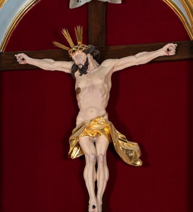 Zdjęcie nr 35: Nastawa architektoniczna, jednoosiowa, jednokondygnacyjna, ustawiona na wysokim cokole. 
Ołtarz drewniany, prostopadłościenny. Na nim tabernakulum z tronem wystawienia. Tabernakulum w formie drewnianej, prostopadłościennej skrzynki, obitej blachą, o wypukłej ściance frontowej, zamkniętej profilowanym gzymsem. Drzwiczki w formie stojącego prostokąta zamkniętego łukiem półkolistym, obwiedzione ramą, z wizerunkiem baranka z krzyżem, leżącego na księdze z pieczęciami, w glorii. Tabernakulum w drewnianej obudowie, wpisane w wysoki cokół, na nim tron wystawienia w formie obrotowej niszy w kształcie stojącego prostokąta, z podwieszoną draperią. Nisza flankowana parą pilastrów, przechodzących w spływy wolutowe, na których siedzą putta. Pilastry dźwigają pełne belkowanie, wyłamane na ich osi, częściowo przerwane przez niszę. Pilastry dekorowane uskrzydlonymi główkami anielskimi oraz snopkiem zboża i kiściami winogron. Cały tron wystawienia dekorowany rocaille'm. 
Nastawa ujęta dwiema parami kolumn o kapitelach kompozytowych, dźwigających pełne belkowanie, wyłamane pomiędzy nimi, przerwane nad polem środkowym. Na belkowaniu fragmenty przerwanego, półkolistego przyczółka, na których leżą putta. Całe pole środkowe wypełnia wnęka w formie stojącego prostokąta zamkniętego łukiem półkolistym, ujęta profilowaną ramą, z figurą Chrystusa Ukrzyżowanego. Nad łukiem wnęki, pomiędzy obłokami, gołębica Ducha Świętego w glorii promienistej. Pomiędzy kolumnami płyciny z uskrzydlonymi główkami anielskimi na obłokach, rocaille oraz figury św.  Jana Ewangelisty i Matki Boskiej na rocaille'owych wspornikach. Kondygnacja ujęta uszami utworzonymi z rocaille'u. Nastawa zwieńczona rzeźbą tronującego Boga Ojca z globem i berłem, pośród obłoków i uskrzydlonych główek anielskich, w glorii promienistej. 
Struktura polichromowana w kolorze błękitnym, kolumny, profile i ornamentyka złocone. 
