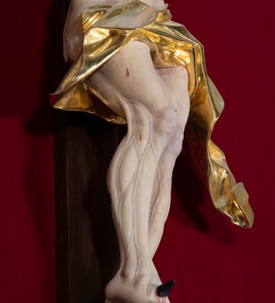 Zdjęcie nr 3: Nastawa architektoniczna, jednoosiowa, jednokondygnacyjna, ustawiona na wysokim cokole. 
Ołtarz drewniany, prostopadłościenny. Na nim tabernakulum z tronem wystawienia. Tabernakulum w formie drewnianej, prostopadłościennej skrzynki, obitej blachą, o wypukłej ściance frontowej, zamkniętej profilowanym gzymsem. Drzwiczki w formie stojącego prostokąta zamkniętego łukiem półkolistym, obwiedzione ramą, z wizerunkiem baranka z krzyżem, leżącego na księdze z pieczęciami, w glorii. Tabernakulum w drewnianej obudowie, wpisane w wysoki cokół, na nim tron wystawienia w formie obrotowej niszy w kształcie stojącego prostokąta, z podwieszoną draperią. Nisza flankowana parą pilastrów, przechodzących w spływy wolutowe, na których siedzą putta. Pilastry dźwigają pełne belkowanie, wyłamane na ich osi, częściowo przerwane przez niszę. Pilastry dekorowane uskrzydlonymi główkami anielskimi oraz snopkiem zboża i kiściami winogron. Cały tron wystawienia dekorowany rocaille'm. 
Nastawa ujęta dwiema parami kolumn o kapitelach kompozytowych, dźwigających pełne belkowanie, wyłamane pomiędzy nimi, przerwane nad polem środkowym. Na belkowaniu fragmenty przerwanego, półkolistego przyczółka, na których leżą putta. Całe pole środkowe wypełnia wnęka w formie stojącego prostokąta zamkniętego łukiem półkolistym, ujęta profilowaną ramą, z figurą Chrystusa Ukrzyżowanego. Nad łukiem wnęki, pomiędzy obłokami, gołębica Ducha Świętego w glorii promienistej. Pomiędzy kolumnami płyciny z uskrzydlonymi główkami anielskimi na obłokach, rocaille oraz figury św.  Jana Ewangelisty i Matki Boskiej na rocaille'owych wspornikach. Kondygnacja ujęta uszami utworzonymi z rocaille'u. Nastawa zwieńczona rzeźbą tronującego Boga Ojca z globem i berłem, pośród obłoków i uskrzydlonych główek anielskich, w glorii promienistej. 
Struktura polichromowana w kolorze błękitnym, kolumny, profile i ornamentyka złocone. 
