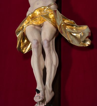 Zdjęcie nr 4: Nastawa architektoniczna, jednoosiowa, jednokondygnacyjna, ustawiona na wysokim cokole. 
Ołtarz drewniany, prostopadłościenny. Na nim tabernakulum z tronem wystawienia. Tabernakulum w formie drewnianej, prostopadłościennej skrzynki, obitej blachą, o wypukłej ściance frontowej, zamkniętej profilowanym gzymsem. Drzwiczki w formie stojącego prostokąta zamkniętego łukiem półkolistym, obwiedzione ramą, z wizerunkiem baranka z krzyżem, leżącego na księdze z pieczęciami, w glorii. Tabernakulum w drewnianej obudowie, wpisane w wysoki cokół, na nim tron wystawienia w formie obrotowej niszy w kształcie stojącego prostokąta, z podwieszoną draperią. Nisza flankowana parą pilastrów, przechodzących w spływy wolutowe, na których siedzą putta. Pilastry dźwigają pełne belkowanie, wyłamane na ich osi, częściowo przerwane przez niszę. Pilastry dekorowane uskrzydlonymi główkami anielskimi oraz snopkiem zboża i kiściami winogron. Cały tron wystawienia dekorowany rocaille&#039;m. 
Nastawa ujęta dwiema parami kolumn o kapitelach kompozytowych, dźwigających pełne belkowanie, wyłamane pomiędzy nimi, przerwane nad polem środkowym. Na belkowaniu fragmenty przerwanego, półkolistego przyczółka, na których leżą putta. Całe pole środkowe wypełnia wnęka w formie stojącego prostokąta zamkniętego łukiem półkolistym, ujęta profilowaną ramą, z figurą Chrystusa Ukrzyżowanego. Nad łukiem wnęki, pomiędzy obłokami, gołębica Ducha Świętego w glorii promienistej. Pomiędzy kolumnami płyciny z uskrzydlonymi główkami anielskimi na obłokach, rocaille oraz figury św.  Jana Ewangelisty i Matki Boskiej na rocaille&#039;owych wspornikach. Kondygnacja ujęta uszami utworzonymi z rocaille&#039;u. Nastawa zwieńczona rzeźbą tronującego Boga Ojca z globem i berłem, pośród obłoków i uskrzydlonych główek anielskich, w glorii promienistej. 
Struktura polichromowana w kolorze błękitnym, kolumny, profile i ornamentyka złocone. 
