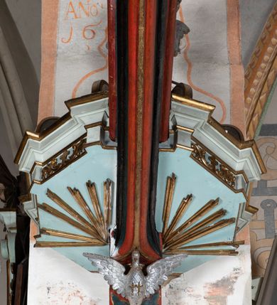 Zdjęcie nr 5: Kosz ambony na planie ośmioboku z szyszką i wolutami u podstawy. Ścianki kosza ujęte pilastrami z karbowaną wstęgą i kampanulami, zakończone od dołu wolutami z motywem liścia akantu oraz wolutą pod kapitelami. W czterech ścianach nisze ze złotymi konchami. W niszach rzeźby czterech ewangelistów z atrybutami. Ponad nimi motywy ornamentalne rocaille z różyczką pośrodku. Na zaplecku tablice Dekalogu na obłoku na tle glorii promienistej. Ujęte w prostokątną ramę zwieńczoną łukiem wklęsło-wypukłym. Baldachim ośmioboczny z podwieszoną glorią i gołębicą, fryz z motywami rocaille&#039;ów i krzyży, wyłamany gzyms. W zwieńczeniu koncentrycznie schodzące się woluty. Ambona polichromowana na kolor seledynowy, detale złocone, postacie w różnobarwnych szatach, partie ciała potraktowane naturalistycznie. 