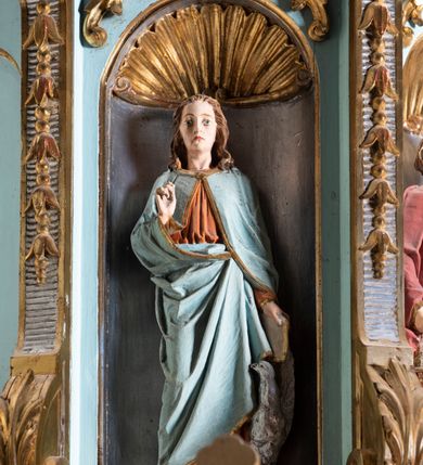 Zdjęcie nr 6: Kosz ambony na planie ośmioboku z szyszką i wolutami u podstawy. Ścianki kosza ujęte pilastrami z karbowaną wstęgą i kampanulami, zakończone od dołu wolutami z motywem liścia akantu oraz wolutą pod kapitelami. W czterech ścianach nisze ze złotymi konchami. W niszach rzeźby czterech ewangelistów z atrybutami. Ponad nimi motywy ornamentalne rocaille z różyczką pośrodku. Na zaplecku tablice Dekalogu na obłoku na tle glorii promienistej. Ujęte w prostokątną ramę zwieńczoną łukiem wklęsło-wypukłym. Baldachim ośmioboczny z podwieszoną glorią i gołębicą, fryz z motywami rocaille'ów i krzyży, wyłamany gzyms. W zwieńczeniu koncentrycznie schodzące się woluty. Ambona polichromowana na kolor seledynowy, detale złocone, postacie w różnobarwnych szatach, partie ciała potraktowane naturalistycznie. 