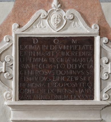 Zdjęcie nr 1: Płyta marmurowa w formie leżącego prostokąta. Ujęta stiukową profilowaną ramą, z fragmentem gzymsu wzdłuż dolnej krawędzi, z uszakami w formie dwóch par spiętych esownic i zwieńczeniem z kartuszem z herbem Gozdawa flankowanym dwiema esownicami. W polu płyty inskrypcja: „D(EO) O(PTIMO) M(AXIMO) / EXIMIA IN DEVM PIETATE / ET IN MARITV INCREDIBI/LI FEMINAE REGINAE MARITAE / SVAE IN CHRISTO DEFV(N)CTAE / GENEROSVS DOMINVS SI/GISMV(N)DVS LINCZEWSKY / MEMORIAE ERGO POSVITQ(UE) / OBIIT DIE IX MENSIS JANV/ARII ANNO D(OMI)NI MDLXXXIII”.